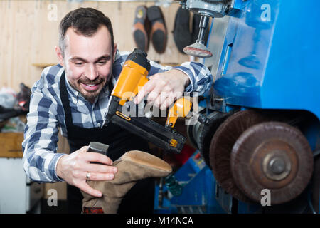 happy american male worker fixing failed shoes in shoe repair workshop Stock Photo