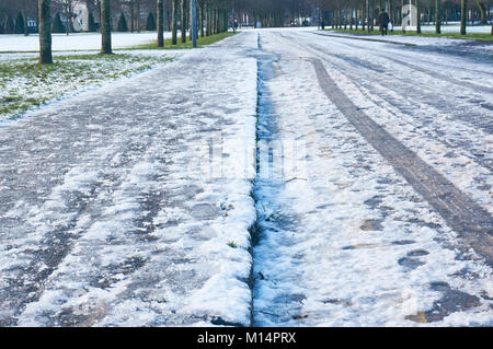Icy road and a pavement covered in frozen snow. Stock Photo