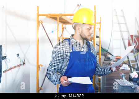 Diligent positive builder is looking on the project of work for the object. Stock Photo