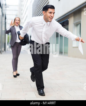 Manager is running away from angry woman boss outdoors. Stock Photo