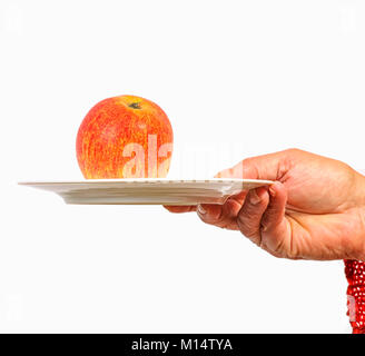 Female hand offers a delicious red apple on a plate Stock Photo