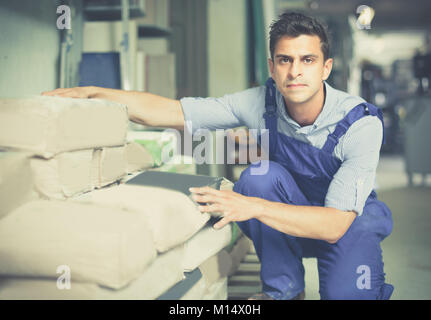 Shop assistant is checking bags with cement in the building store. Stock Photo