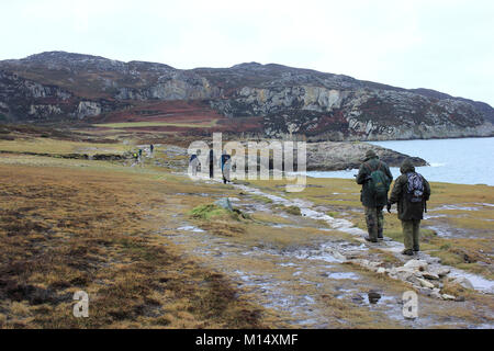 Winter Walkers Along the Rocky Shoreline at Breakwater Country Park below Holyhead Mountain, Anglesey Stock Photo