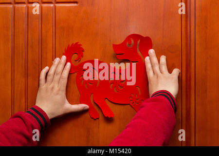 man sticking a Chinese New Year of the Dog 2018 to a door Stock Photo