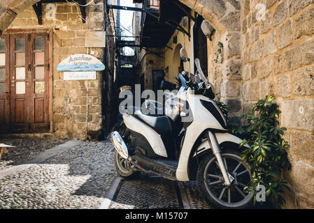 RHODES, GREECE - AUGUST 2017: Motorbike scooters are parked near the wall at narrow street of Rhodes town on Rhodes island, Greece Stock Photo