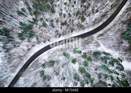 Aerial view of winter road in snowy forest. Drone captured shot from above. Stock Photo