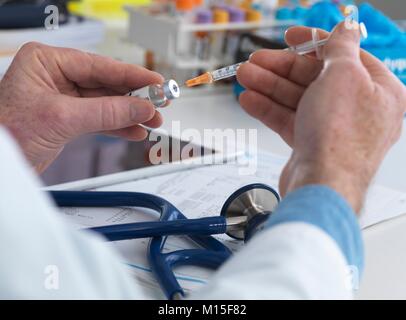 MODEL RELEASED. Doctor preparing a syringe ready for injection. Stock Photo