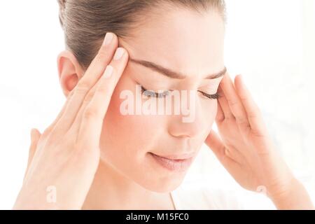 MODEL RELEASED. Young woman in pain rubbing her temples. Stock Photo
