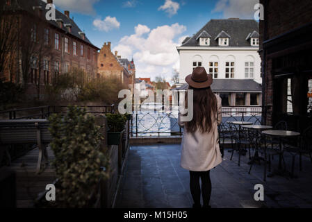 Unrecognizable woman staying back in romantic place in the old town. Female tourist is inspired by atmosphere of vintage buildings on river promenade Stock Photo