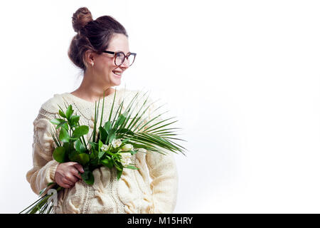 Young woman in a woolen sweater of milky color on the last days of pregnancy holding in her hands a bouquet of beautiful irises flowers and supports t Stock Photo