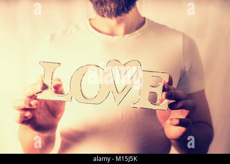 Man holding word Love at wall background Stock Photo