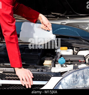 Cropped image of woman pouring windshield washer fluid into car Stock Photo