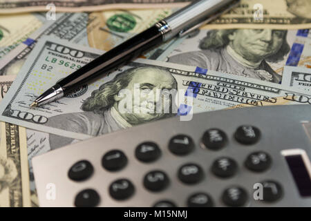 Business background. Calculator and pen lying on the background of money. Close-up Stock Photo