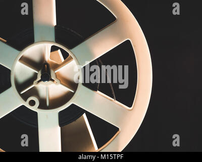 Old 8mm film projector playing in the night in dark room. Rotation reel with tape on the video, audio tape recorder or player. Close-up of a reel with a film. Stock Photo