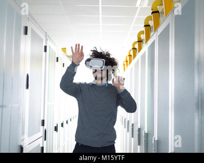 young IT engeneer using virtual reality headset over server room background Stock Photo