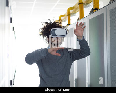 young IT engeneer using virtual reality headset over server room background Stock Photo