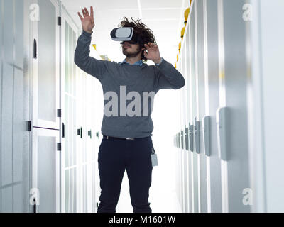 young IT engeneer using virtual reality headset over server room background Stock Photo