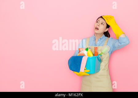 pretty elegant housewife cleaning house long time feeling tired and getting headache painful isolated on pink background. Stock Photo