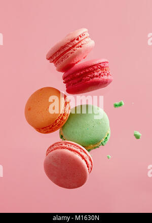 Different types of macaroons in motion falling on pink background. Sweet and colourful french macaroons falling or flying in motion. Stock Photo