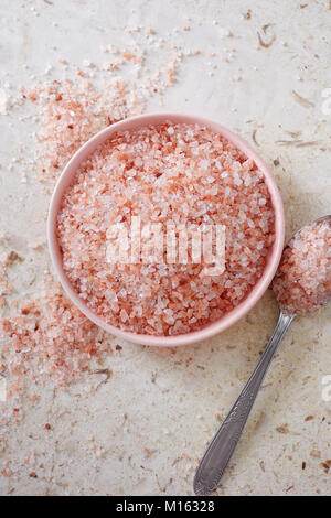 Pink Himalayan salt in the small pink bowl on marble surface. Stock Photo