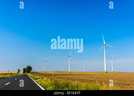 Windmills beside the road for renewable energy production from alternative energy sources like wind power Stock Photo