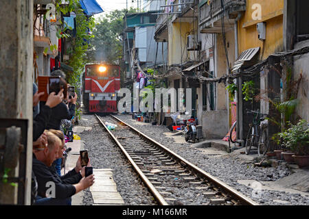 Hanoi, Vietnam - 16th December 2017. Tourists take photos of 15.30 train from Hanoi to Sapa as it goes along a residential street in central  Hanoi Stock Photo