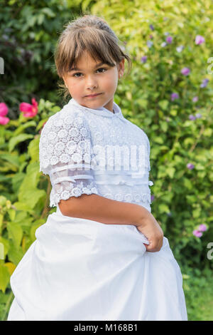 Portrait of little girl in white bridesmaid clothes posing outdoors. Vertically. Stock Photo