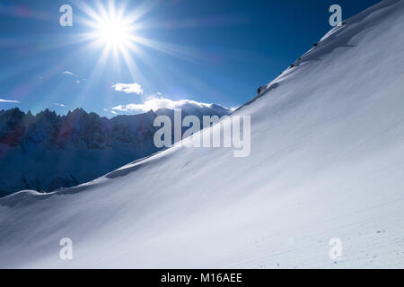 Mountain side and ridge covered in fresh powder snow with Mont Blanc massif in the background on sunny blue sky morning Stock Photo