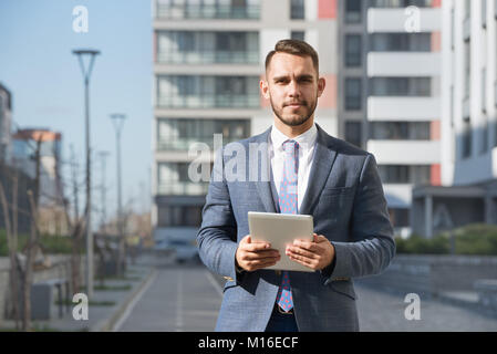 Businessman or real estate agent with tablet computer against new building Stock Photo
