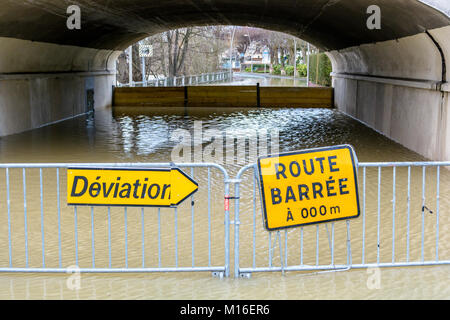 Yellow road signs installed on temporary gates show a traffic diversion in front of a tunnel flooded by the water of the river Marne. Stock Photo