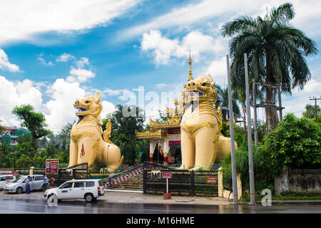 Pair of yellow chinthe statues, leogryph lion-like dragon, standing in front of Nga Htat Gyi Pagoda, protecting it and gaurding Yangon, Myanmar, Burma Stock Photo