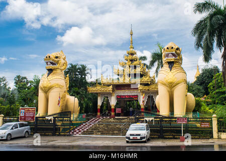 Pair of yellow chinthe statues, leogryph lion-like dragon, standing in front of Nga Htat Gyi Pagoda, protecting it and gaurding Yangon, Myanmar, Burma Stock Photo