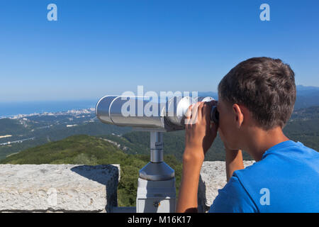 Boy looks at Sochi through binoculars from a tower on a mountain Big Ahun, Krasnodar region, Russia Stock Photo