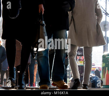 Blurry crowd of people walking towards in rush hour on city street in winter, legs in low angle view Stock Photo