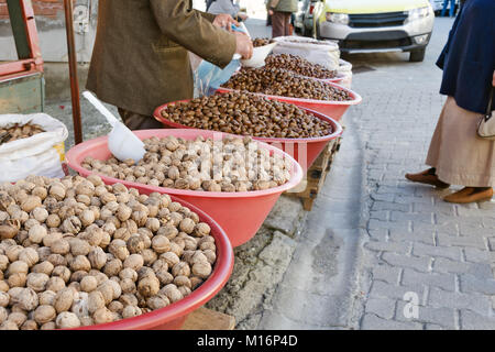 Walnuts and chestnuts are selling on the street in the Turkish village in large plastic bowl. Stock Photo