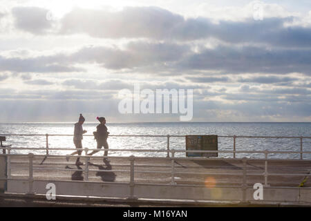 Hastings, East Sussex, UK. 27th Jan, 2018. UK Weather: Sunny intervals in Hastings this morning, lots of people out and about strolling along the sea front promenade viewing the spectacular display of crepuscular rays (sun rays) on show. Two female runners on the seaside promenade. Photo Credit: Paul Lawrenson / Alamy Live News Stock Photo