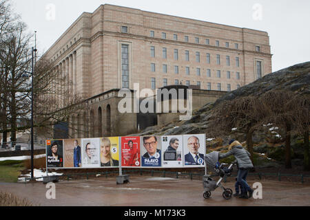 Helsinki, Finland, 27th January, 2018. People on the street at the posters of Presidential candidates against the House of Parliament. Elections will held tomorrow Credit: StockphotoVideo/Alamy Live News Stock Photo