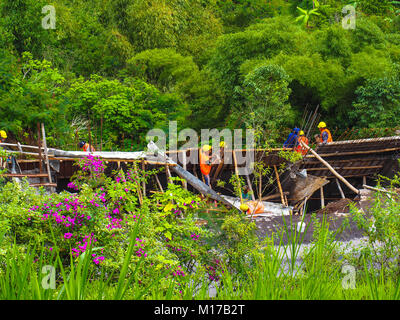 Asian workers on a road construction site in the middle of tropical forest Stock Photo