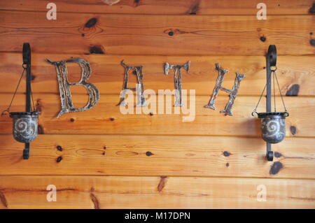 Distressed metal letters spelling out the word 'BATH' mounted on a knotty pine background. Stock Photo