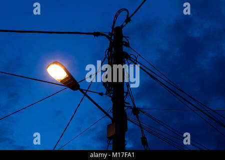Overhead rural electricity power lines and telephone lines on a pole in a rural village in the U.K. Stock Photo