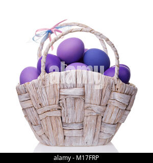 Basket full of eggs colored in shades of violet isolated on white background Stock Photo