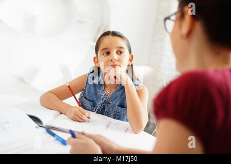 Hispanic Mother Helping Girl Doing School Homework At Home Stock Photo