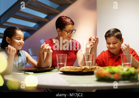 Dinner At Home With Happy Family Praying Before Eating Stock Photo