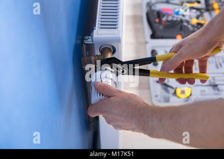 Close-up Of A Young Male Repairman Fixing Radiator With Wrench Stock Photo