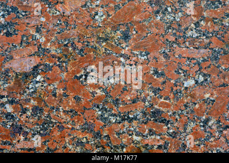 Red grey granite background and wallpaper. Blotches of red granite in a gray mass of natural stone. Stock Photo