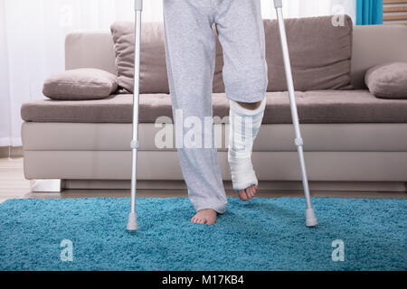 Man With Broken Leg Using Crutches For Walking On Blue Carpet Stock Photo