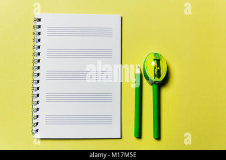 notebook and a green pencil on yellow background. Office theme Stock Photo