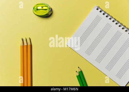 Sharpener, notebook, pencils on a yellow background. Office theme Stock Photo