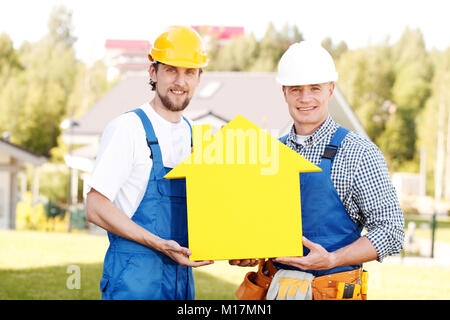 Construction workers showing house model symbol and friendly smiling Stock Photo