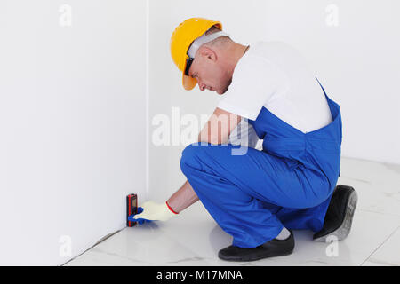 The worker makes finishing works of walls using laser line level. Laser roulette device Stock Photo